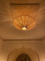 Natural raffia flush mount ceiling light with round handwoven sunburst design and metal frame.