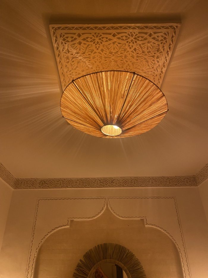 Natural raffia flush mount ceiling light with round handwoven sunburst design and metal frame.