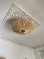 Natural raffia flush mount ceiling light with round handwoven sunburst design and metal frame.
