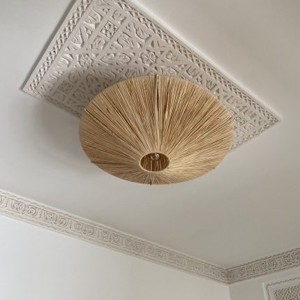 Natural raffia flush mount ceiling light with round handwoven sunburst design and metal frame.