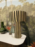 Black and natural raffia table lamp with vertical striped design, tall cylindrical base and wide handwoven drum lampshade.