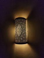 Handmade Moroccan pierced brass wall lamp with perforated pattern and warm up and down lighting.
