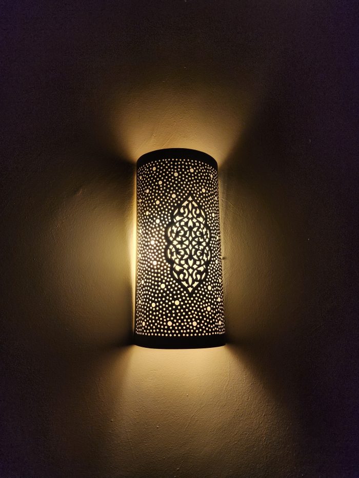 Handmade Moroccan pierced brass wall lamp with perforated pattern and warm up and down lighting.