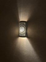 Handmade radiant rosette brass wall sconce with central geometric floral medallion and pierced decorative pattern.