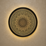 Handmade Moroccan brass wall light with round pierced floral design and warm halo illumination.