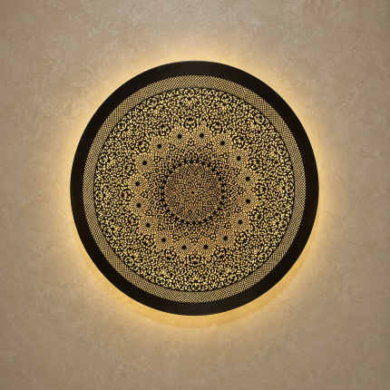 Handmade Moroccan brass wall light with round pierced floral design and warm halo illumination.