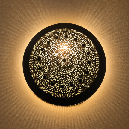 Handmade round brass wall light with intricate mandala pattern and radiant warm halo illumination.