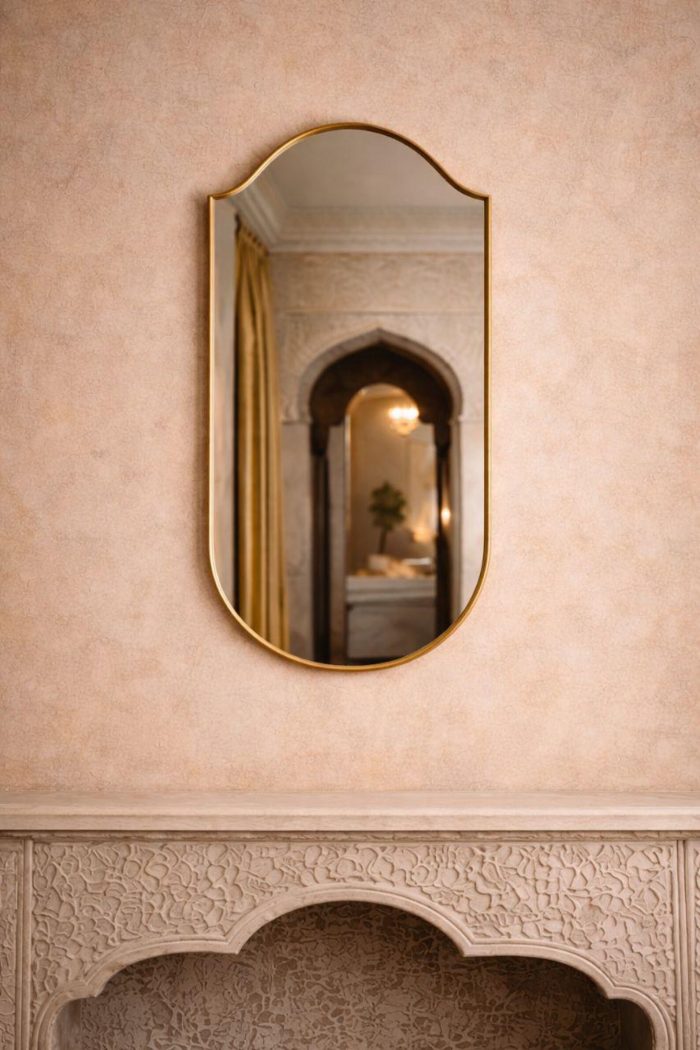 Handmade curved crown brass wall mirror with softly arched top and solid brass frame above bathroom vanity.