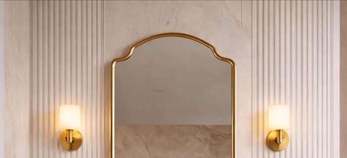 Crown Curve Brass Mirror above wood vanity with green tiled bathroom wall