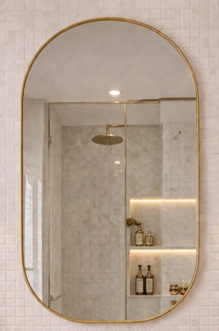 Handmade rounded arch brass wall mirror with solid brass frame above a double bathroom vanity.
