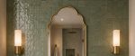 Handmade triple arch brass wall mirror with solid brass frame and clear glass displayed above a bathroom vanity.