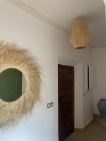 Handwoven palm leaf mirror with round glass center and natural sunburst fringe wall decor