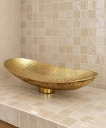 Hand hammered brass vessel sink with elongated oval shape and textured golden finish